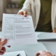 Primer plano de un solicitante de empleo entregando su currículum durante una entrevista de trabajo en la oficina.